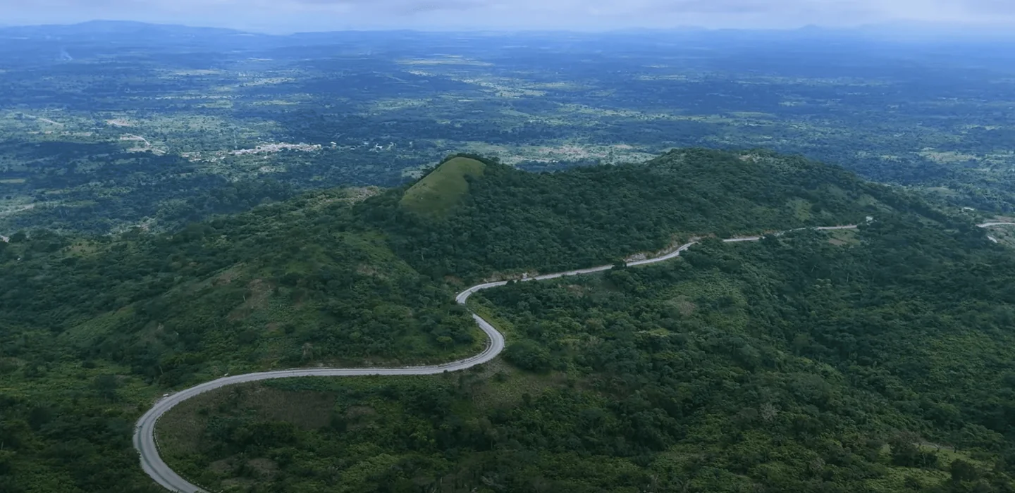 Aerial view of a winding road across forested mountain ridges