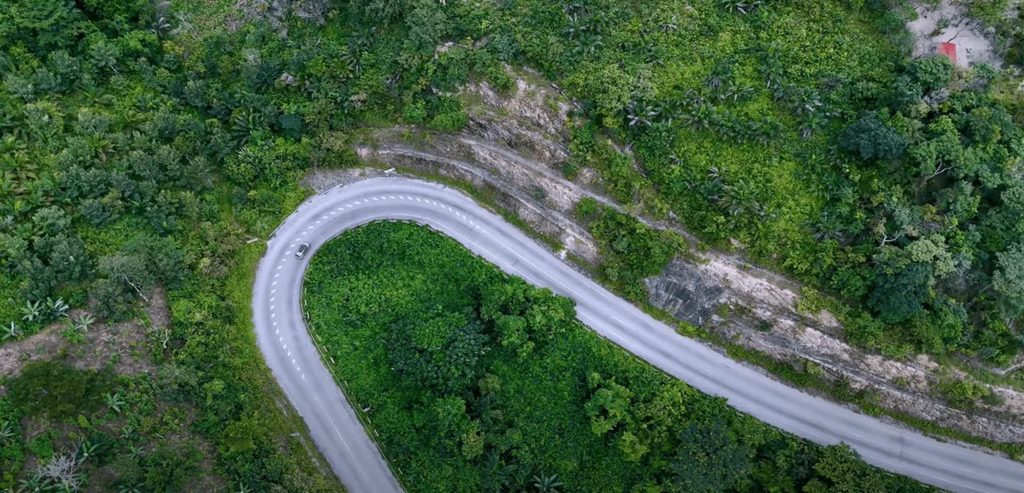 A winding mountain road seen from above amid dense green vegetation