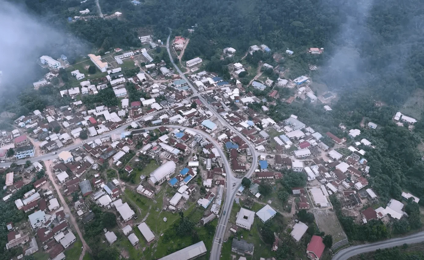 Aerial view of a mountain village surrounded by forest and mist